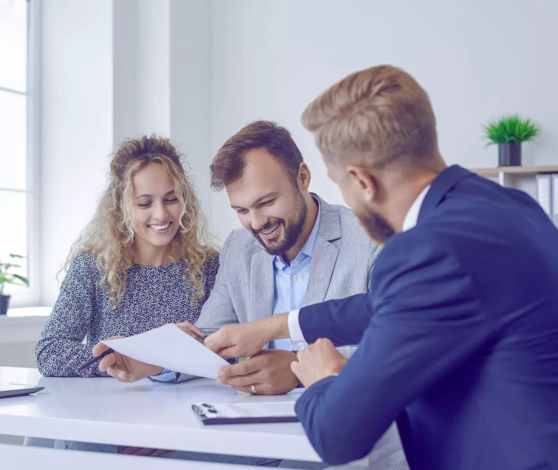 a financial advisor meeting with a couple and showing them information on a piece of paper